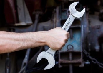 Hand holding wrench on dark background plombier a domicile